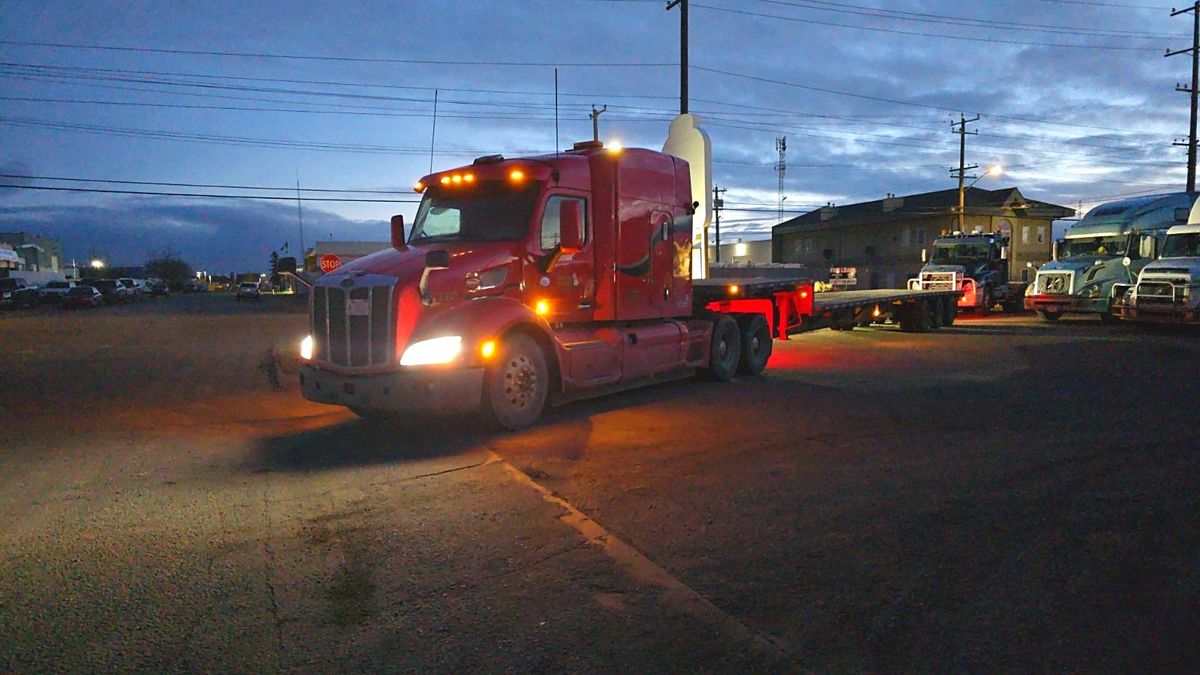 Red flatdeck truck leaving the Edmonton yard at dusk